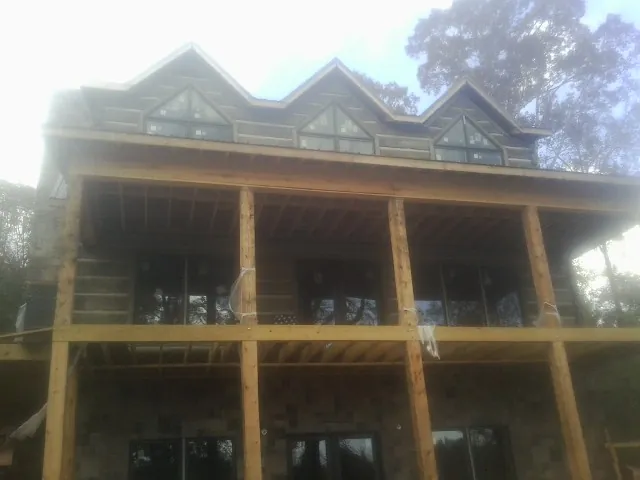 Dormers and porch framing on a large log home under construction — Roof Coating work by our crew in Mayport