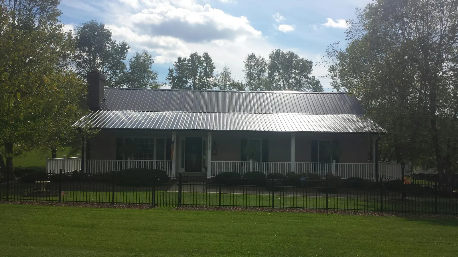 Gray metal roof on a brick ranch with a full width front porch — Gutter Guard Installation work by our crew in Mayport