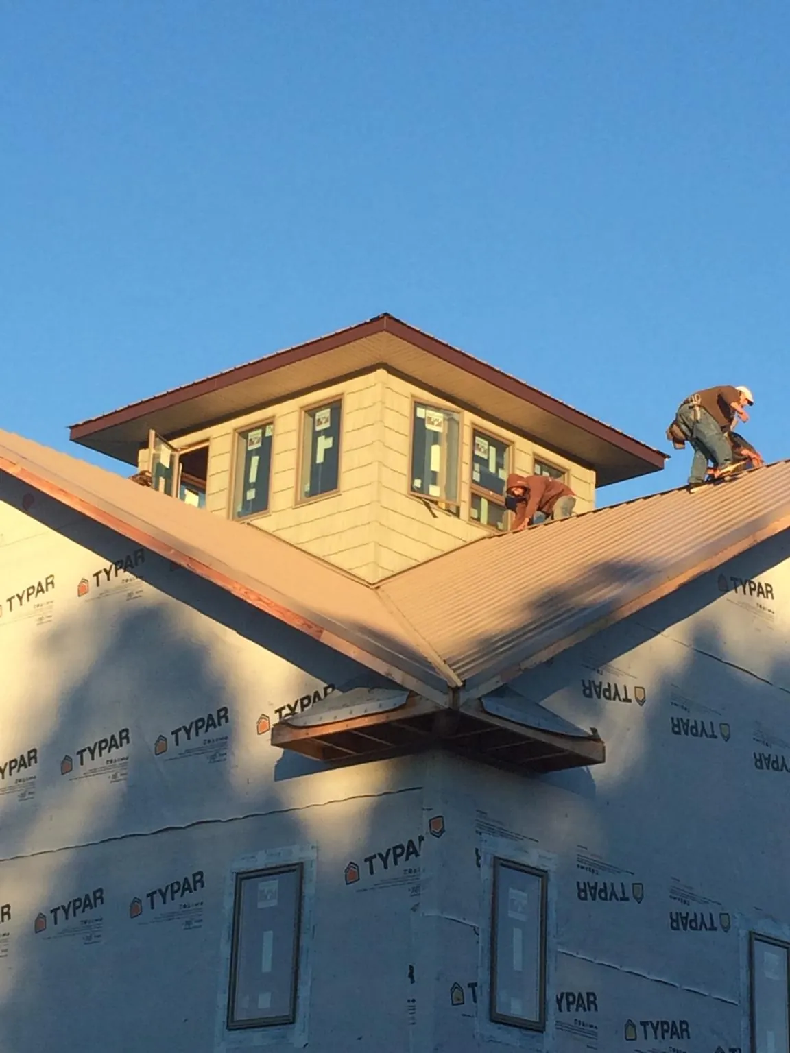 Roofers working around a rooftop cupola on a new metal roof at sunset — Roof Waterproofing in Mayport by Roofing Brothers
